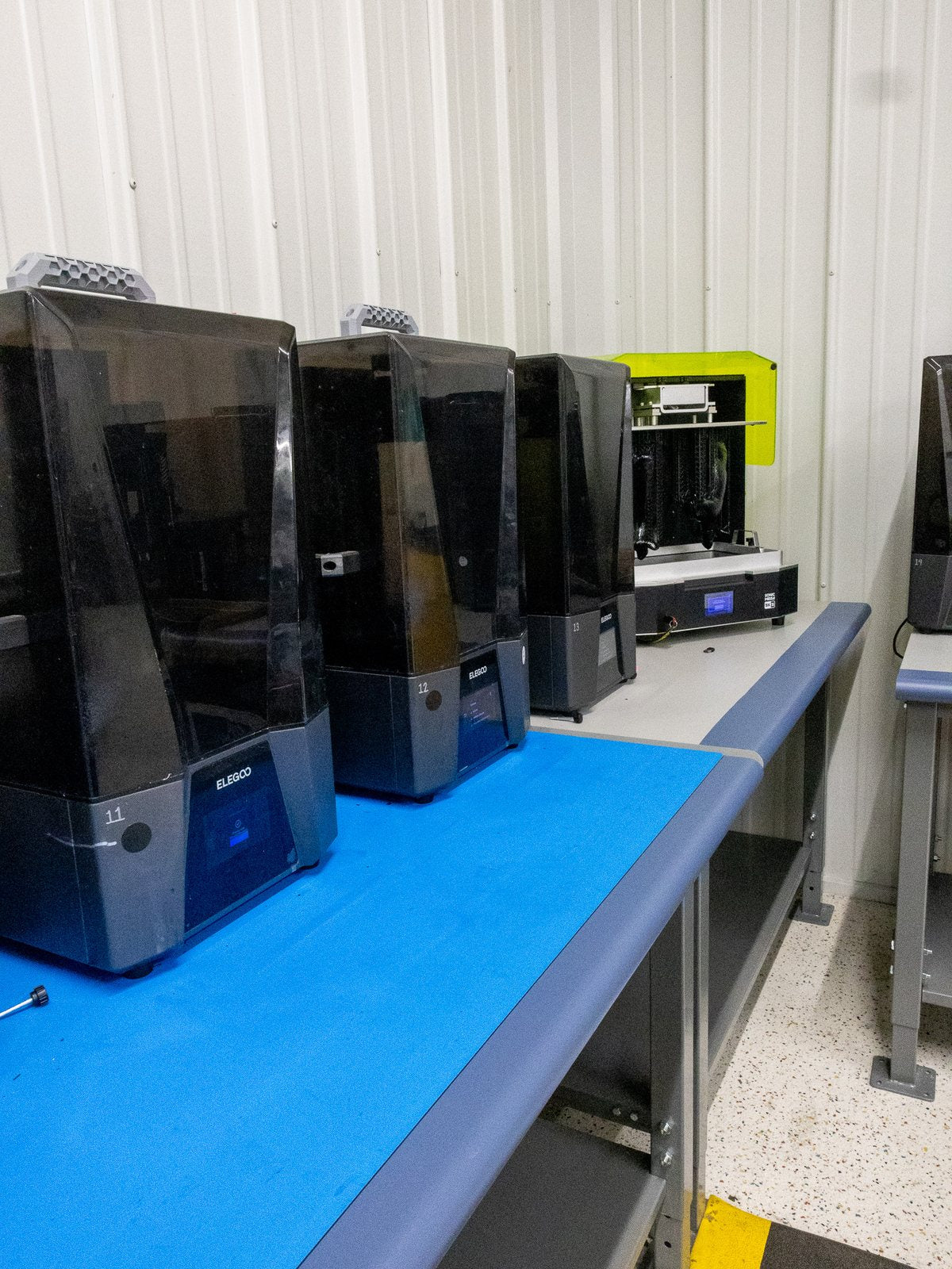A numbered bank of MSLA resin printers on the bench beside the wash and cure station